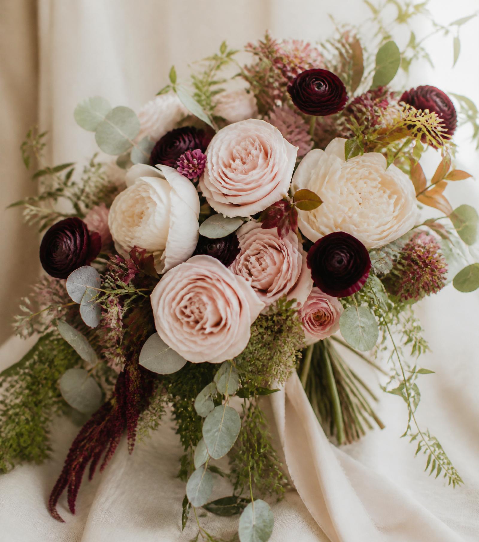 Handcrafted bridal bouquet of blush garden roses, cream peonies and burgundy ranunculus